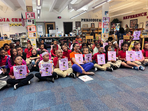 Students in a class sit with author Clothilde Ewing, holding up one book in her published series “Stella.” The series aims to resonate with children because of the main character’s determination and creativity.
