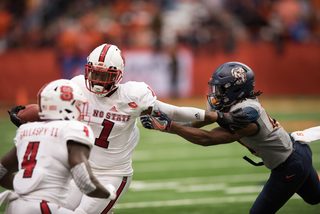 The Wolfpack's Jaylen Samuels stiff arms a Syracuse defender.