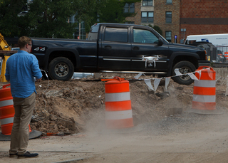 A worker guides a drone back to ground at the South Crouse Avenue construction site, which will soon be home to a new multiuse complex. Photo taken Aug. 1, 2017